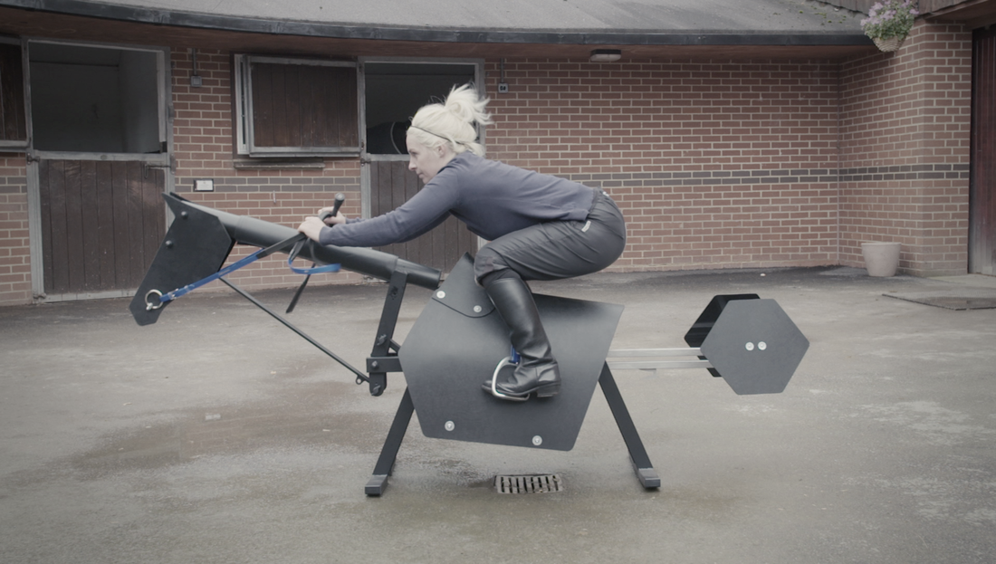 A person riding a black horse riding simulator outdoors, with a foldable design and exercise equipment attached.
Made in UK by Racewood. Available with Nice equestrian Wukair Doha Qatar.