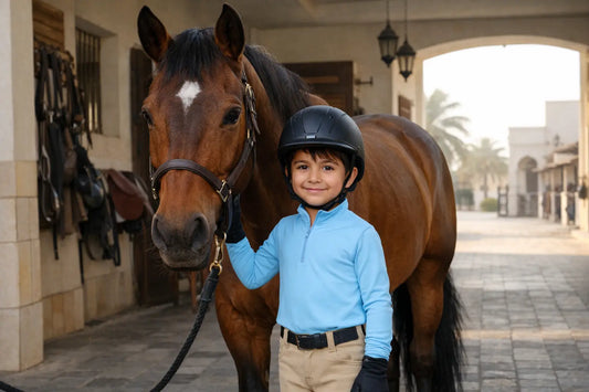 Child wearing riding tights and UPF riding top at a horse stable in Qatar — clothing guide for parents